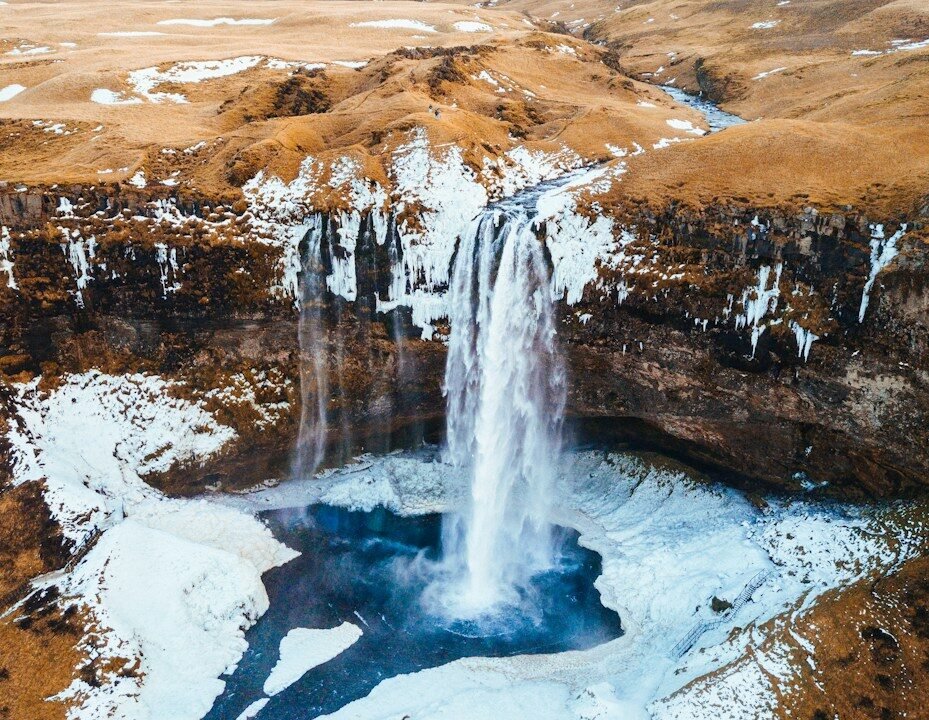 aerial photography of waterfalls near mountains at daytime