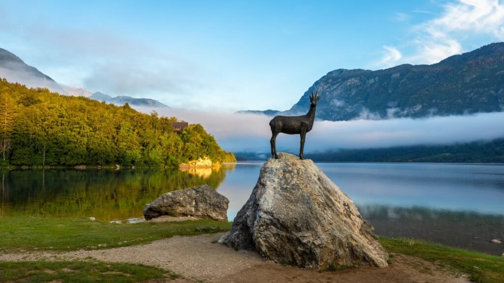 Early morning view at Lake Bohinj in Bohinj with the statue of Goldhorn (Zlatorog) on the rock.