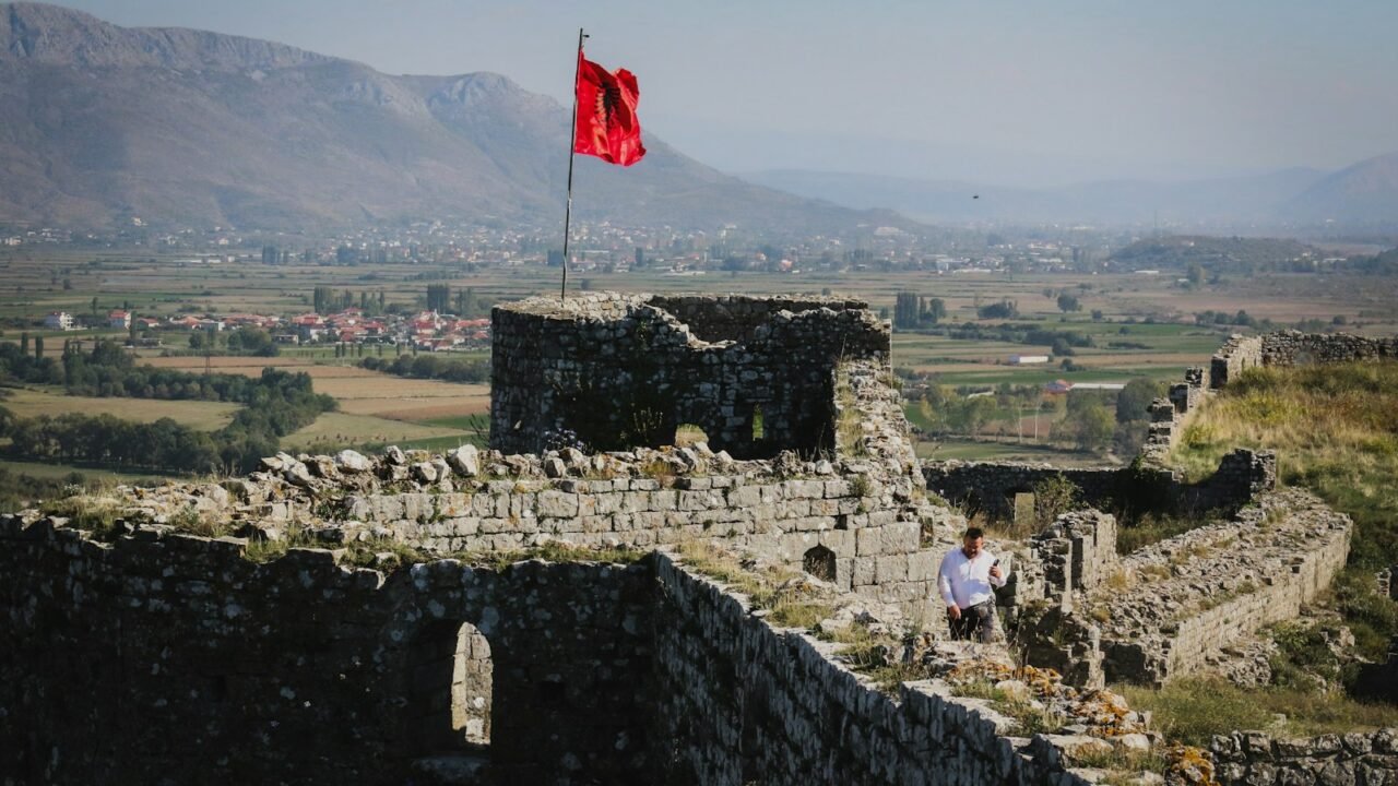 a man sitting on a stone wall next to a flag