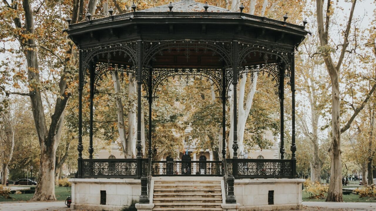 black and white gazebo surrounded with tall and orange trees